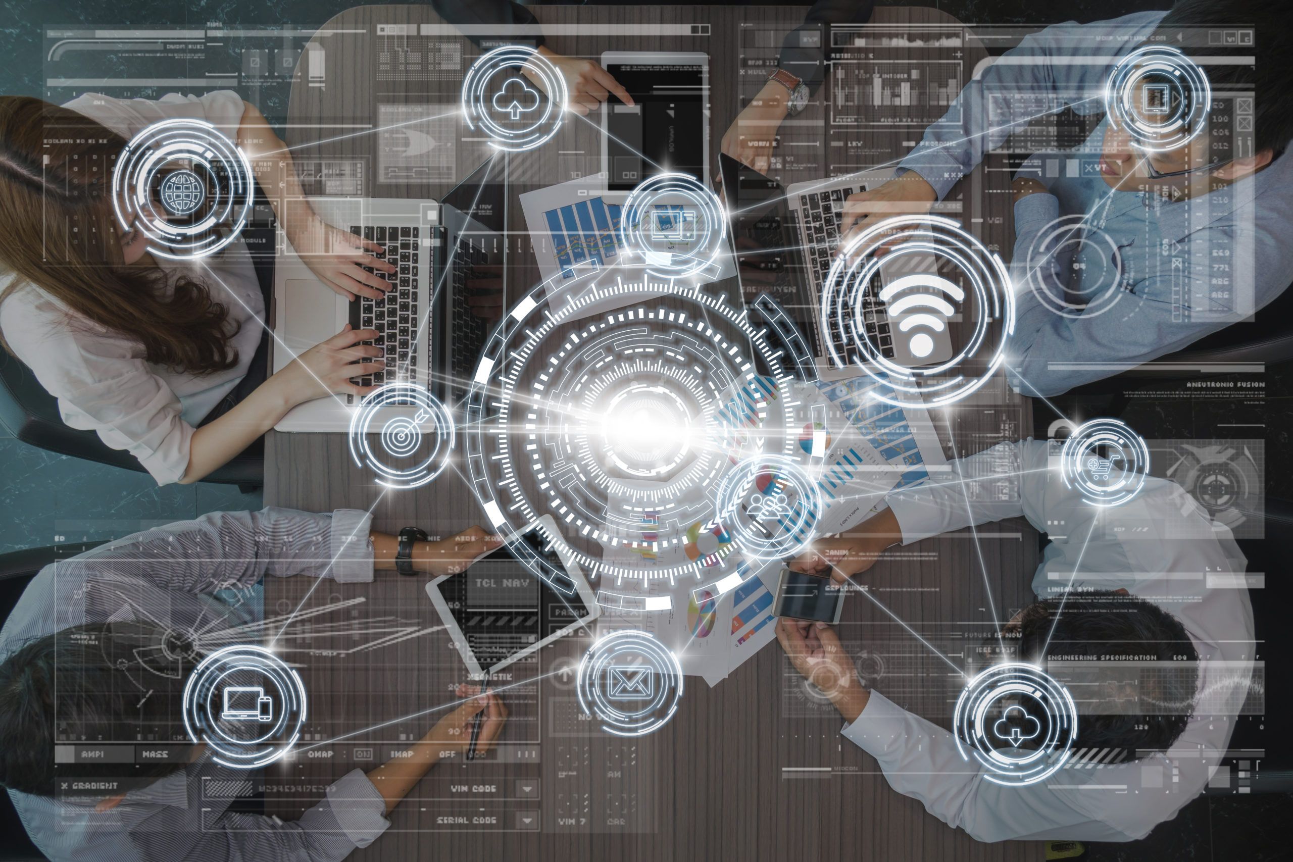 Overhead view of a business team collaborating with laptops and documents, overlaid with digital icons representing wireless