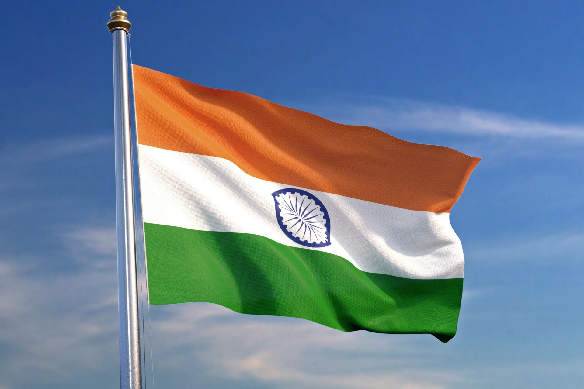 Indian tricolor flag with saffron, white, and green bands and Ashoka Chakra waving against a clear blue sky.