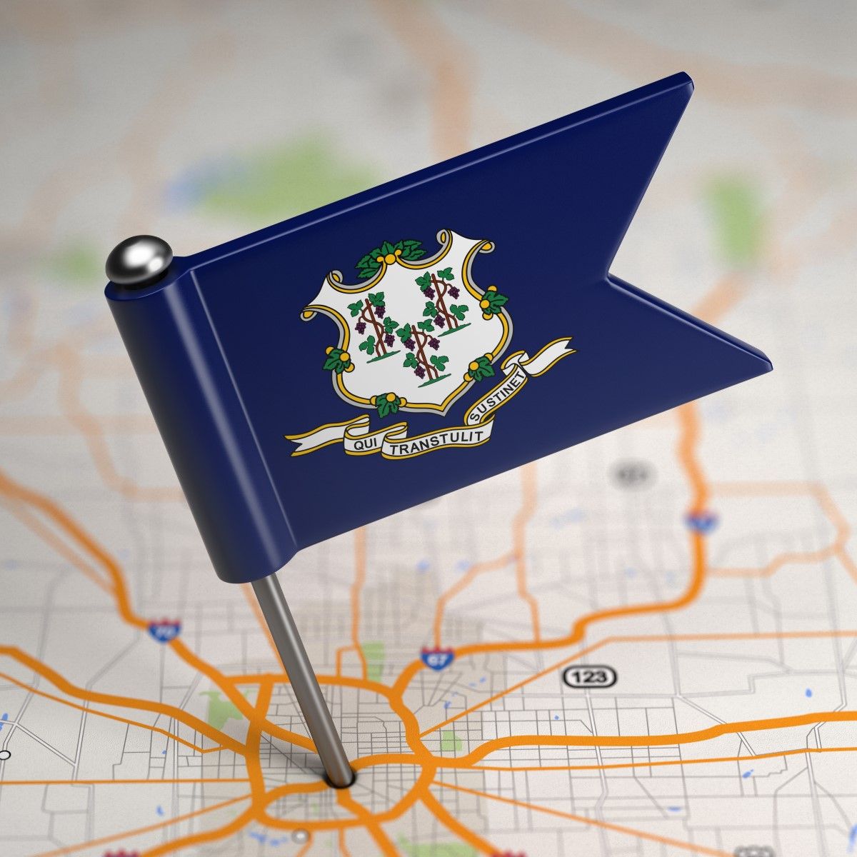 Small Connecticut state flag pinned into a road map, featuring the state's coat of arms and Latin motto.